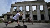UKRAINE -- A boy ride his scooter in front of the destroyed building of the city hall in the city of of Okhtyrka, Sumy region on August 1, 2022,