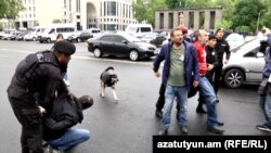 Полицейский задерживает протестующего, который пытается перекрыть движение транспорта на одной из центральных улиц Еревана. 2 мая 2022 года