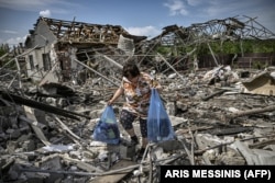 Женщина собирает остатки имущества у своего разрушенного ракетным обстрелом дома. Славянск, Донбасс, 1 июня 2022 года