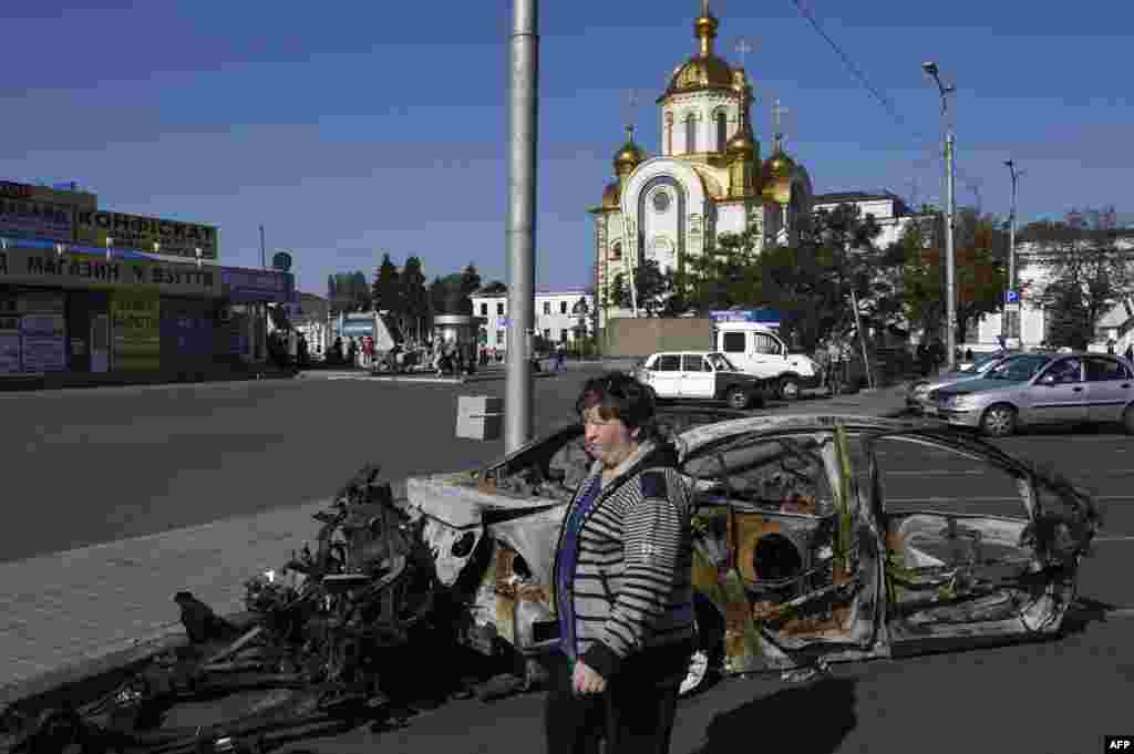 Ukraine -- A woman walks past a burnt car near the railway station in Donetsk, September 15, 2014