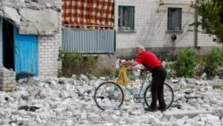 Мужчина толкает велосипед мимо разрушенного дома в Рубежном 1 июня 2022 года