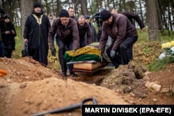 An imam and others attend the November 18, 2021 funeral of an African migrant at a Tatar cemetery near eastern Poland's village of Bohoniki, not far from the Polish-Belarusian border. The unnamed migrant is one of several migrants who have died from various causes while waiting in frigid temperatures to enter Poland.