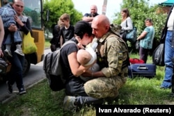 Женщина с ребенком на руках после выхода из колонны эвакуации из оккупированного российскими войсками города Купянска на окраине Харькова. Украина, 30 мая 2022 года