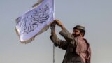 AFGHANISTAN -- A Taliban fighter raises their flag on a vehicle as they patrol in Kandahar, August 17, 2021