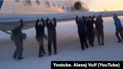 Krasnoyarsk, Igark. Men push the plane, which is frozen to the runway. 26 Nov 2014 