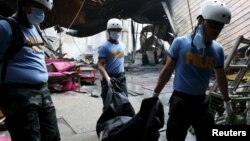 Пожарные вытаскивают тела погибших в пожаре на фабрике в Маниле 