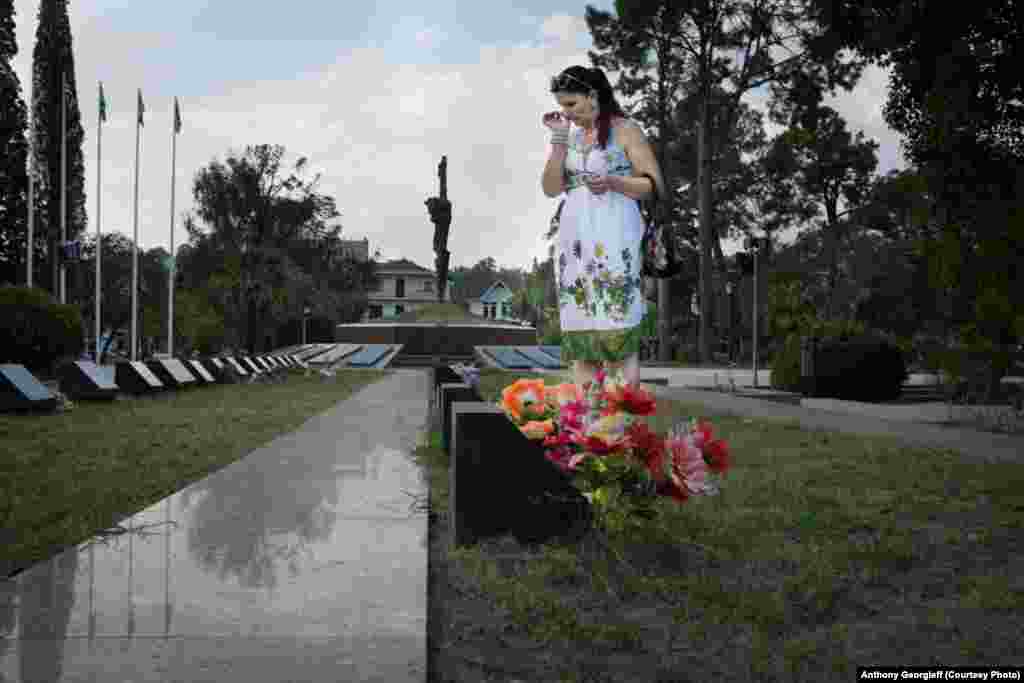 Женщина возлагает цветы на могилу родственника, погибшего во время войны 1992-93 годов. Одна из центральных площадей Сухуми превращена в мемориальное кладбище. 