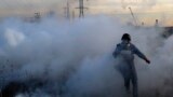 Palestine -- Palestinian press photographers run amidst tear gas smoke during clashes with Israeli forces on December 11, 2017 near the border fence with Israel, east of Gaza City.