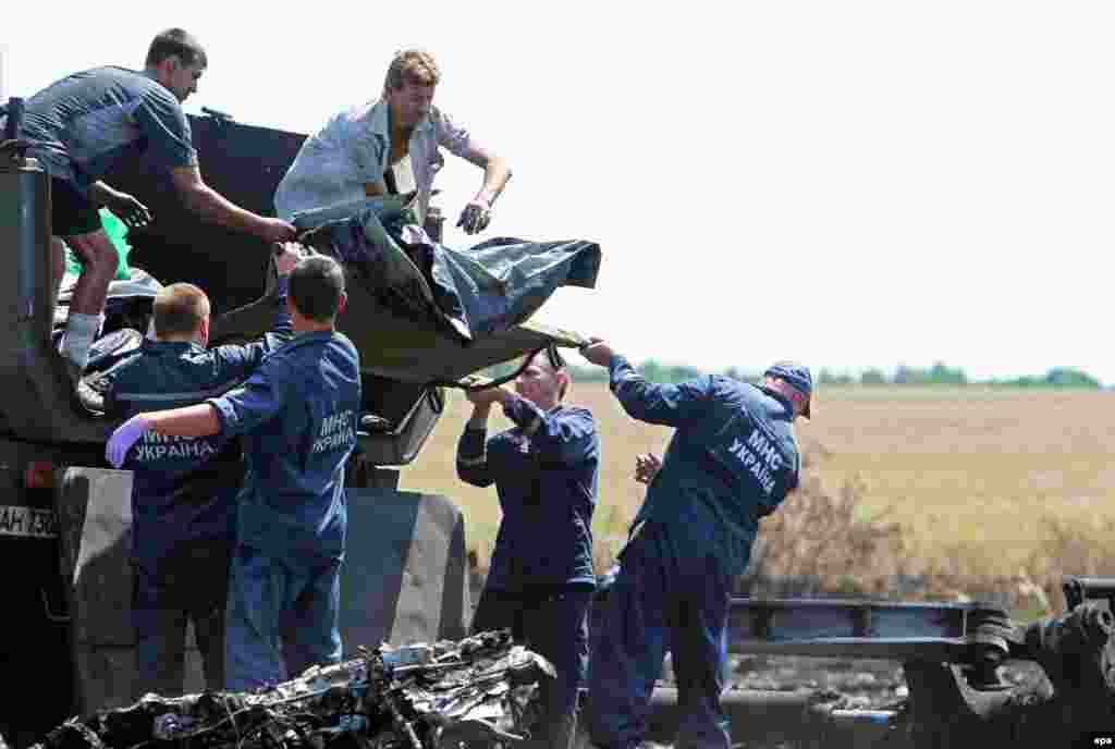 Сотрудники министерства по чрезвычайным ситациям Украины разбирают обломки самолета. 21 июля 2014 года