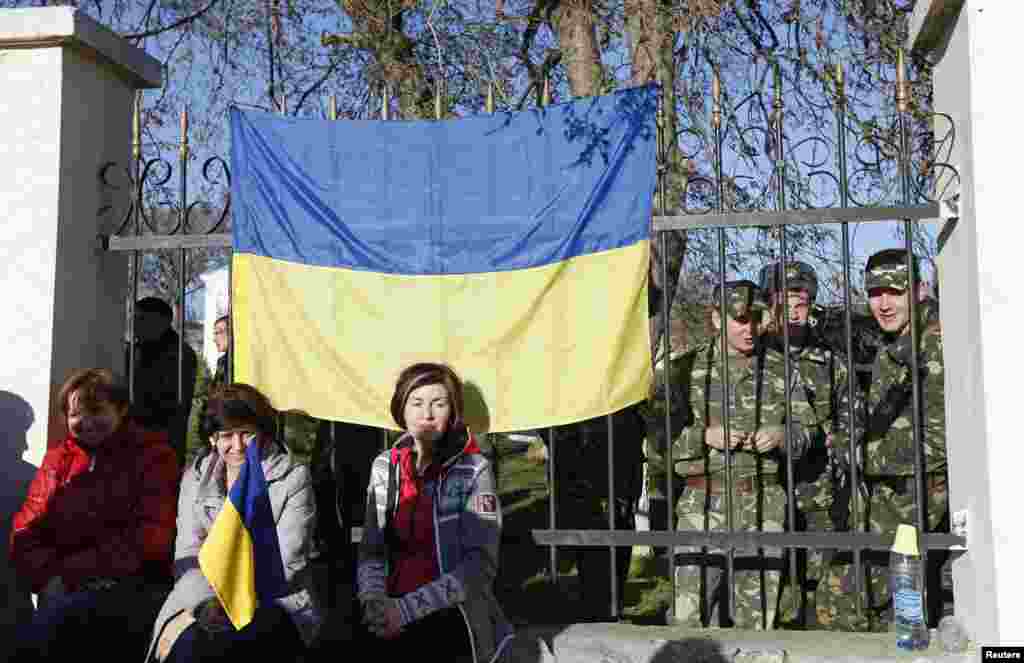 В поселке Любимовка украинские военнослужащие собираются на территории воинской части. Их родственники сидят у забора, чтобы не допустить вооруженных столкновений, 3 марта 2014