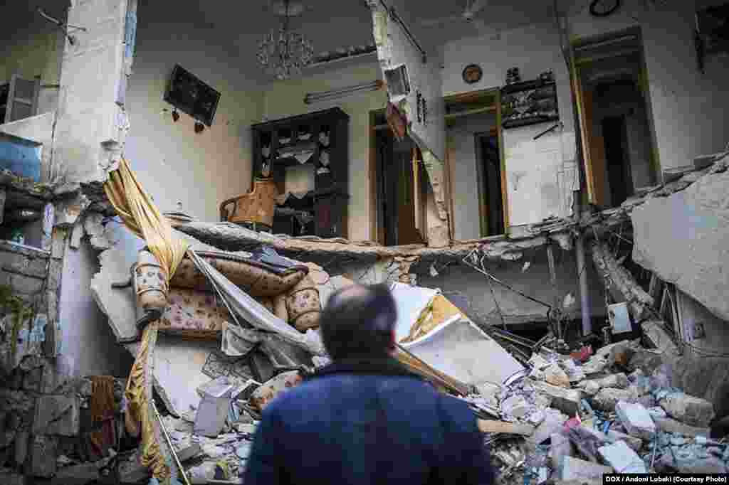 Мужчина смотрит на дом, разрушенный после рейда войск Башара Асада в Алеппо (Сирия). Район аль-Изаа был одним из густонаселенных во всем городе. Во время боев он был сильно разрушен. Фото сделано 3 января 2013 года