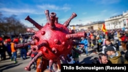 Иллюстративное фото: модель коронавируса на акции протеста против правительственных ограничений в Германии, весна 2020 года. Источник: Reuters