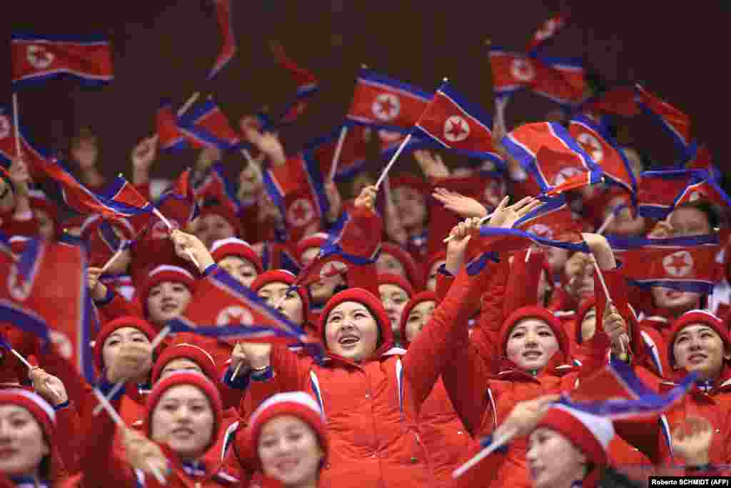 Девушки размахивают флагами КНДР во время соревнований в короткой программе в парном катании. 14 февраля 2018