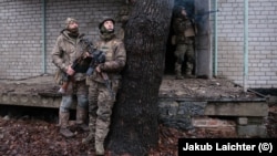 "Француз" (слева) и "Сява" (опирается на дерево) наблюдают за дроном во время тренировки