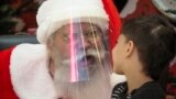 RUSSIA - An actor dressed as Santa Claus and wearing a face mask to protect against coronavirus infection speaks with a boy during the New Year celebration in a shopping mall in St.Petersburg, Russia, Saturday, Jan. 2, 2021