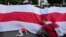 POLAND - Protesters carrying the white-and-red banner of the Belarusian opposition march past the U.S. Embassy in Warsaw, Poland, on Sunday, Aug. 8, 2021