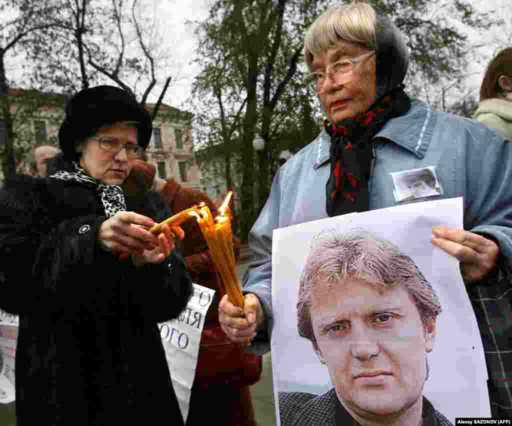 Women hold a poster of Litvinenko and light candles during a Moscow memorial on November 22, 2008.&nbsp;