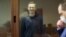 RUSSIA -- This screen grab from a handout footage provided by the Babushkinsky district court on February 16, 2021, shows Russian opposition leader Alexei Navalny, charged with defaming a World War II veteran, looking from inside a glass cell during a cou