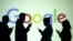 Silhouettes of mobile users are seen next to a screen projection of Google logo - generic