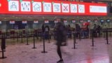 Geneva, Switzerland - People wearing protective masks walk in the departure terminal of Cointrin airport, the day the Swiss government imposed a 10 days quarantine for travellers who have entered from Britain, during the outbreak of the coronavirus diseas