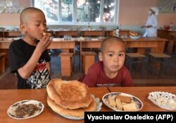 Two evacuees from Kyrgyz districts bordering Tajikistan eat in the dining room of a public school in the Kyrgyz town of Batken that serves as a shelter for the displaced from Kyrgyzstan and Tajikistan's April 28-April 29, 2021 border conflict.
