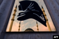 На металлической панели в центре Грозного - силуэт женщины в платке, иллюстрирующий мечеть "Сердце Чечни". Фото AFP, июль 2017 года