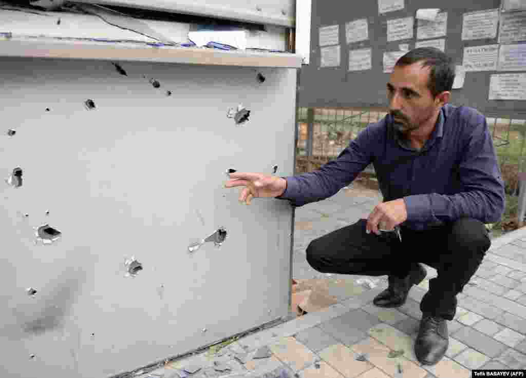 A man shows a kiosk damaged during shelling on the Azerbaijani town of Tartar.