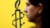 The logo of Amnesty International is seen next to director of Mujeres En Linea Luisa Kislinger, during a news conference to announce the results of an investigation into humans rights abuses committed in Venezuela during protests against President Nicolas