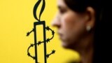 The logo of Amnesty International is seen next to director of Mujeres En Linea Luisa Kislinger, during a news conference to announce the results of an investigation into humans rights abuses committed in Venezuela during protests against President Nicolas
