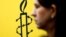 The logo of Amnesty International is seen next to director of Mujeres En Linea Luisa Kislinger, during a news conference to announce the results of an investigation into humans rights abuses committed in Venezuela during protests against President Nicolas