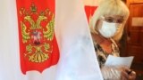 Village of Gigirevo in Moscow region, Russia - A woman wearing a protective mask and gloves, used as a preventive measure against the spread of the coronavirus disease (COVID-19), leaves a voting booth at a polling station during a seven-day vote on const