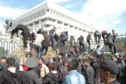 Протестующие взбираются на забор у здания парламента в Бишкеке. 3 октября 2012