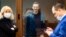RUSSIA -- Russian opposition leader Aleksei Navalny smiles as he talks with his lawyers Olga Mikhailova, left, and Vadim Kobzev during a hearing on his charges for defamation in the Babuskinsky District Court in Moscow, February 16, 2021