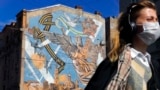 RUSSIA -- A woman wearing a face mask to protect against coronavirus walks past a graffiti dedicated to the victory of the Soviet Union in the World War II, in St. Petersburg, May 4, 2020