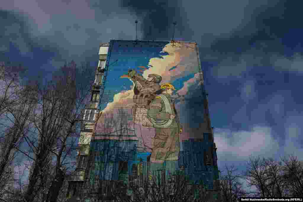 На граффити "Защитники света" изображен солдат, охраняющий небо от российских ударов, а также сотрудник энергетической компании, который готов ремонтировать поврежденные обстрелами энергетические объекты