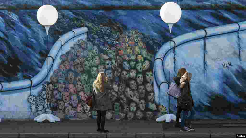 Люди гуляют вдоль&nbsp;стендов с воздушными шарами, размещенными&nbsp;вдоль бывшей Берлинской стены. 7 ноября 2014 