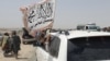 PAKISTAN - People wave a Taliban flag as they drive through the Pakistani border town of Chaman on July 14, 2021, after the Taliban claimed they had captured the Afghan side of the border crossing of Spin Boldak along the frontier with Pakistan