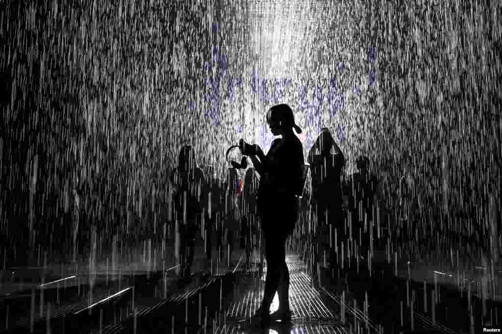 Люди в Комнате дождя, инсталляции Random International в музее в Шанхае. В комнате идет дождь, прекращаясь в тех местах, где находятся посетители, позволяя им остаться сухими, 1 сентября 2015&nbsp;