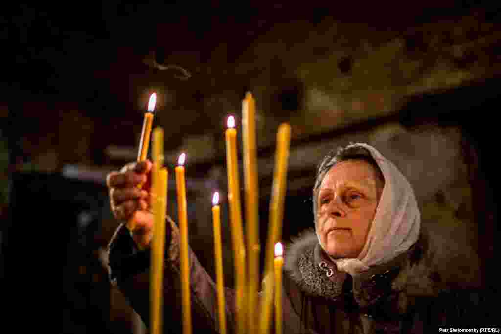 Прихожанка зажигает свечи на Пасхальной службе в храме в Петровском районе Донецка&nbsp;