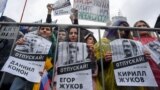 Люди на акции протеста держат плакаты с фотографиями арестованных по "московскому делу". 10 августа 2019 года. Фото: AFP