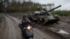 Местный житель едет на скутере мимо подбитого российского танка в Изюме, 14 сентября 2022 года