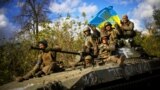 UKRAINE – Ukrainian soldiers sit on an armoured vehicle as they drive on a road between Izium in Kharkiv Oblast and the city of Lyman in Donetsk Oblast, October 4, 2022 