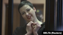 Belarusian opposition activist Maryya Kalesnikava, charged with extremism and trying to seize power illegally, forms a heart shape with her hands inside a defendants' cage during her September 6, 2021 court hearing in Minsk. 