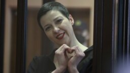 Belarusian opposition activist Maryya Kalesnikava, charged with extremism and trying to seize power illegally, forms a heart shape with her hands inside a defendants' cage during her September 6, 2021 court hearing in Minsk. 