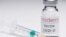 This creative image taken in a studio in Paris on November 16, 2020, showing a syringe and a vaccine vial with the reproducted logo of a US biotech firm Moderna, illustrates the announcement of an experimental vaccine against Covid-19 from Moderna that wo