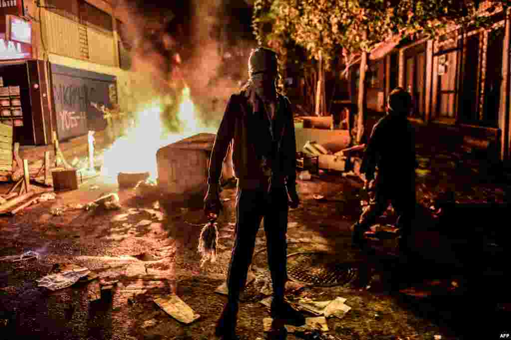Курд, вооруженный бутылкой с зажигательной смесью, на фоне горящей баррикады во время столкновений с турецкой полицией в районе Гази в Стамбуле. &nbsp;
