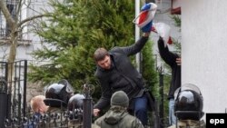 Депутат Владимир Парасюк прыгает через забор российского консульства во Львове сорванным российским флагом в руке
