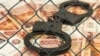 Generic -- Metal handcuffs on the background of Russian rubles under wire netting