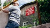 Жилец забаррикадированного строителями дома карабкается через бетонные блоки, чтобы попасть на свой участок. Фото: "Большая деревня"