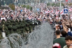 Колючая проволока между военными, окружившими стелу "Минск – город-герой", и демонстрантами. 23 августа